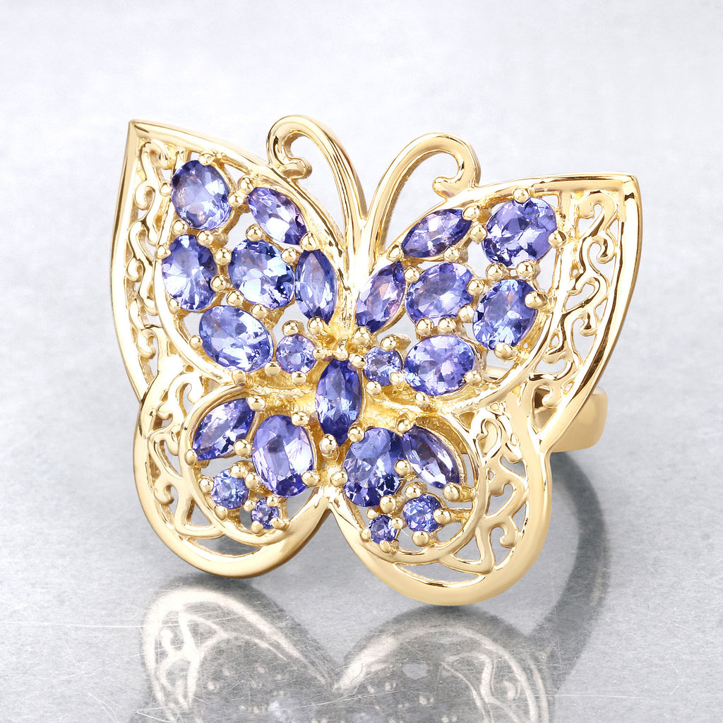 Gold butterfly-shaped jewelry with purple gemstones on a light gray background