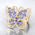 Gold butterfly-shaped jewelry with purple gemstones on a light gray background